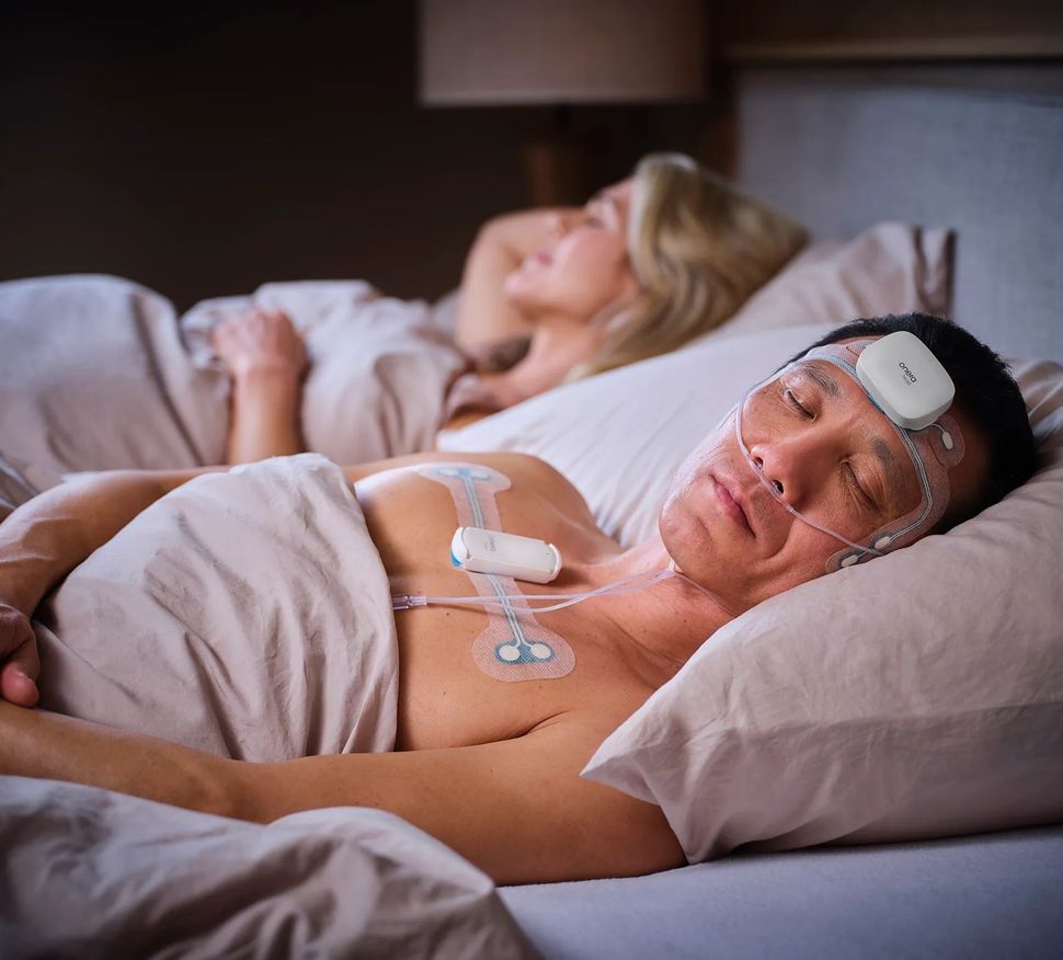 Man sleeping in bed with diagnostics patches on forehead and chest