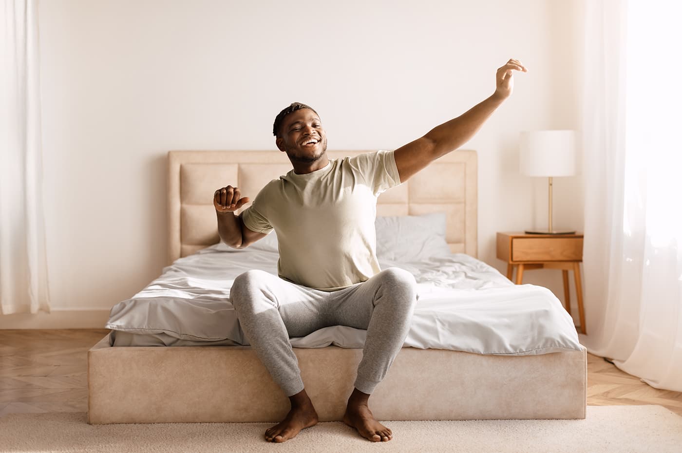 man sitting and stretching at end of bed